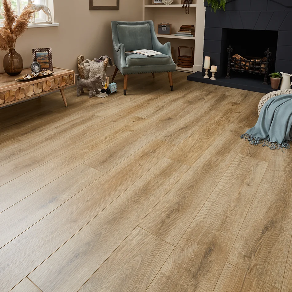 Wide plank oak laminate flooring in a warm living room with a fireplace and velvet armchair