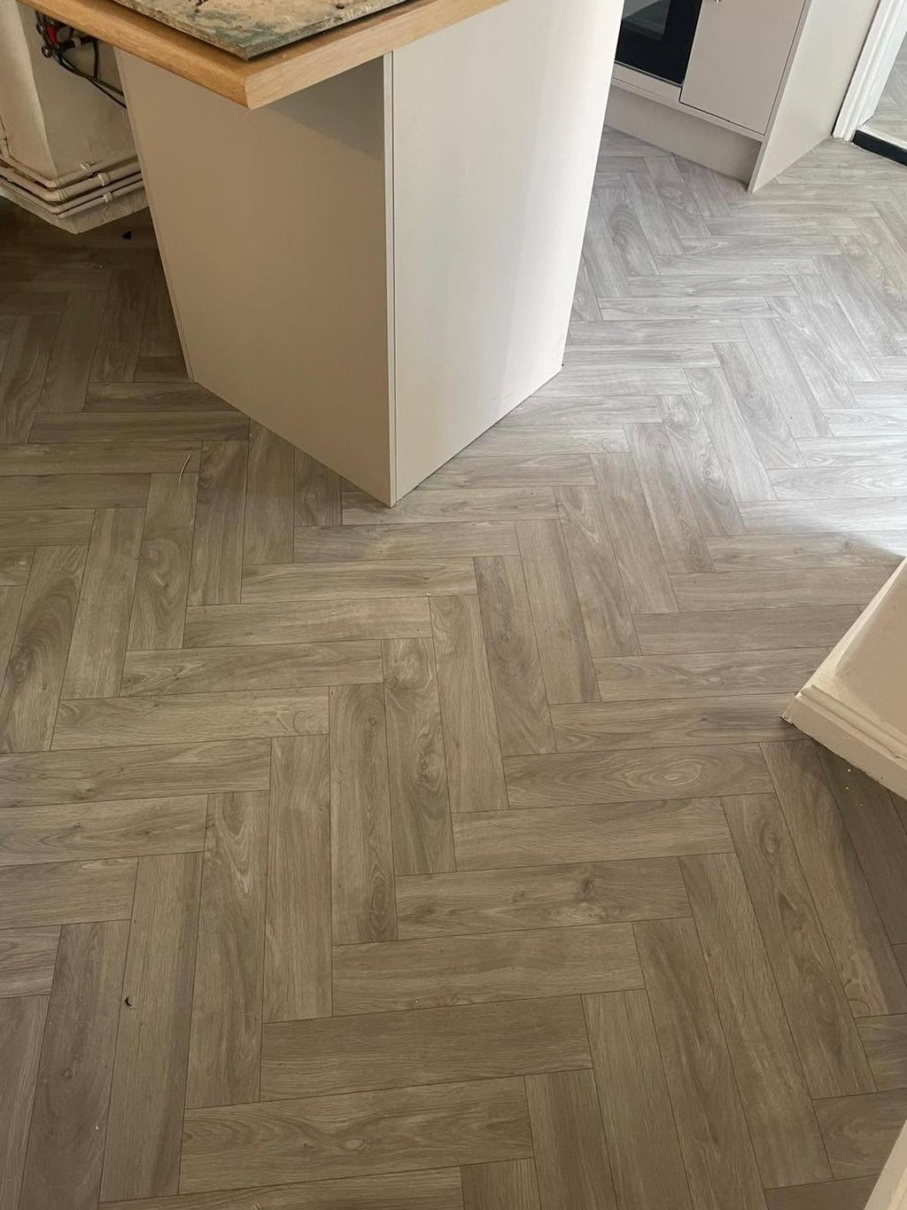 Light oak herringbone laminate flooring fitted in a kitchen